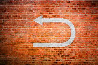 arrow turning backward on brick wall