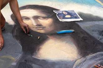 artist finishing sidewalk chalk drawing of mona lisa
