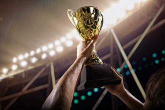 athlete holding trophy cup above head in stadium