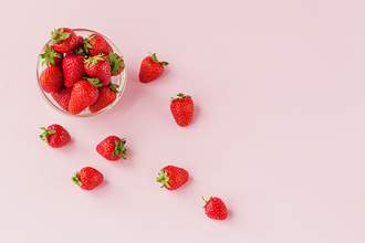 bowl of strawberries on pink background