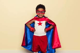 boy in superhero costume with hands on hips