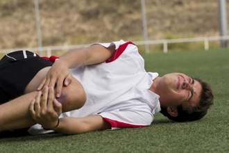 boy laying on the ground in pain holding his knee