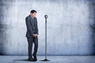 business man look shy while standing in front of a microphone
