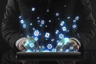 business man working on a tablet while poker icons fly out of the screen