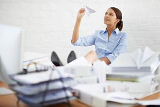 business woman sitting at her desk getting ready to throw a paper airplane