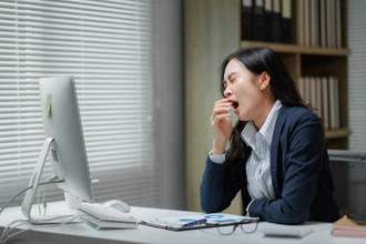 business woman sitting at her desk yawning
