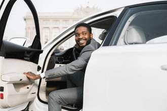 businessman smiling as he gets out of a car