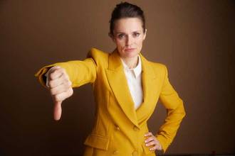 businesswoman giving thumbs down while looking at the camera
