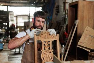 carpenter using sand paper to smooth out details in custom chair