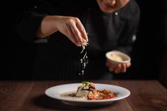 chef garnishing a dish with cheese