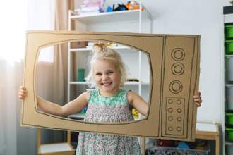 child playing with cardboard tv