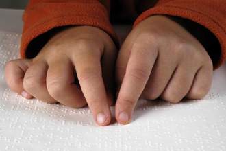 child reading braille with their fingers