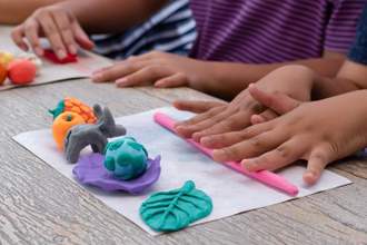 child rolling out molding clay to make a small sculpture