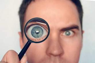 close up of a man holding up a magnifying glass to his eye