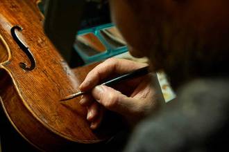close up of a man working on restoring a violin