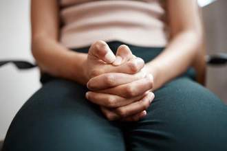 close up shot of a person sitting nervously holding their hands tightly together