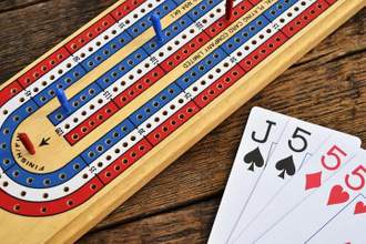 colorful cribbage board and cards sitting on a wooden table