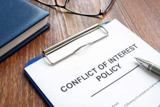 conflict of interest policy and pen on a wooden surface