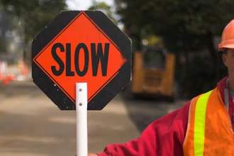 construction worker holding up a slow sign toward traffic