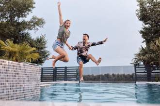 couple fully clothed jumping spontaneously into a pool