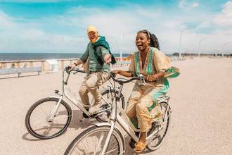 couple riding bikes along the beach while looking lovingly at each other