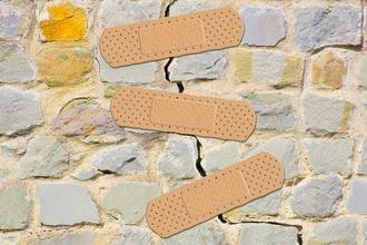cracked and damaged stone wall being patched with bandages