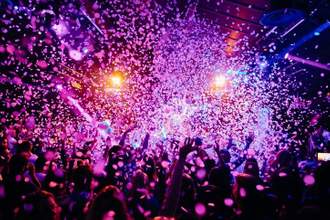 crowd of people at a concert with their hands in the air and confetti in the sky
