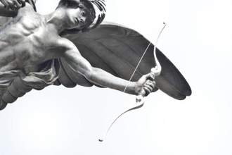 cupid statue leaning into the frame pointing an arrow