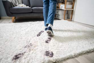 dirty shoes tracking mud on white carpet