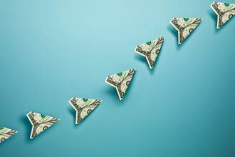 dollar bills folded into airplanes in a row going up