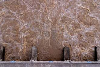 downward view of a dam with brown water flowing through