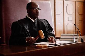 experienced male judge sitting at desk with wooden gavel