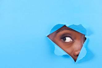 eye poking through a ripped hole in a blue background
