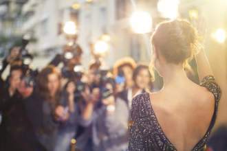 famous actress at a movie premiere waving to the paparazzi
