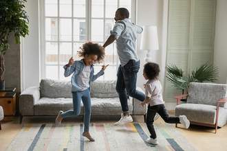 father and children dancing in living room