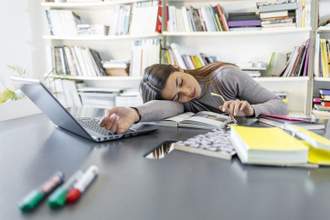 female student who fell asleep on the desk in the library with a pile of books