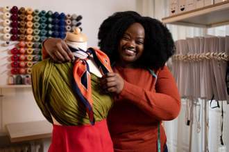 female stylist looking excited adding a colorful scarf to a new outfit