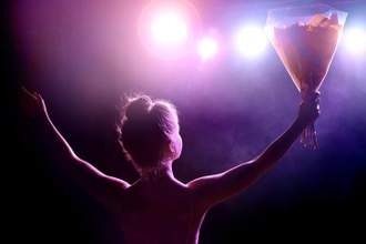 girl holding out her arms looking out to an adoring crowd