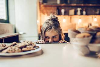 girl looking at cookies on counter
