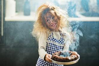 girl looking sweet after she burnt the cake she is holding