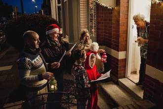 group of carolers singing to a woman in front of her home