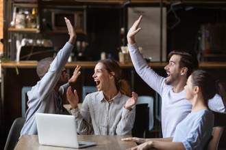 group of friends celebrating after watching a game on their laptop