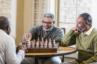 group of older men sitting at a table playing chess