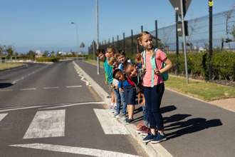 group of school children looking both ways before crossing the street