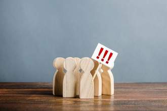 group of wooden pegs that look like humans standing together in protest