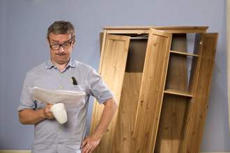 guy looking confused at the instructions with a wrecked cabinet in the background