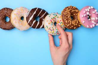 hand choosing donut from row of donuts