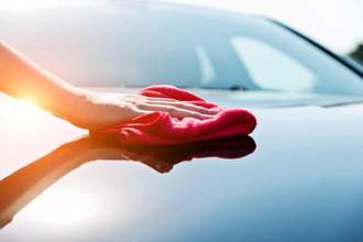 hand drying the vehicle hood with a red towel
