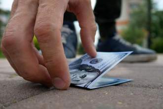 hand reaching down to grab money that they found on the sidewalk
