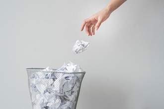 hand throwing paper into trash